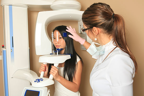 A hygienist taking a digital x-ray on 3d cone beam scanner.