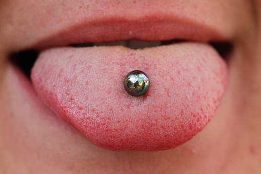 A person with a tongue piercing sticking out tongue