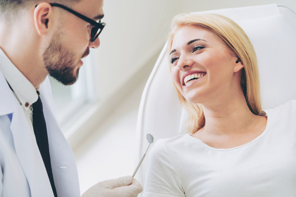 Woman smiling while oral surgeon talks about surgical procedures at Surf City Oral and Maxillofacial Surgery in Huntington Beach, CA